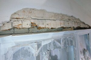 Ausbau des Retabels Der Putz oberhalb des Retabels ist entfernt, man erkennt das Backsteinmauerwerk des Turms und sieht, dass das Retabel mit einem Holzkeil fixiert wurde.